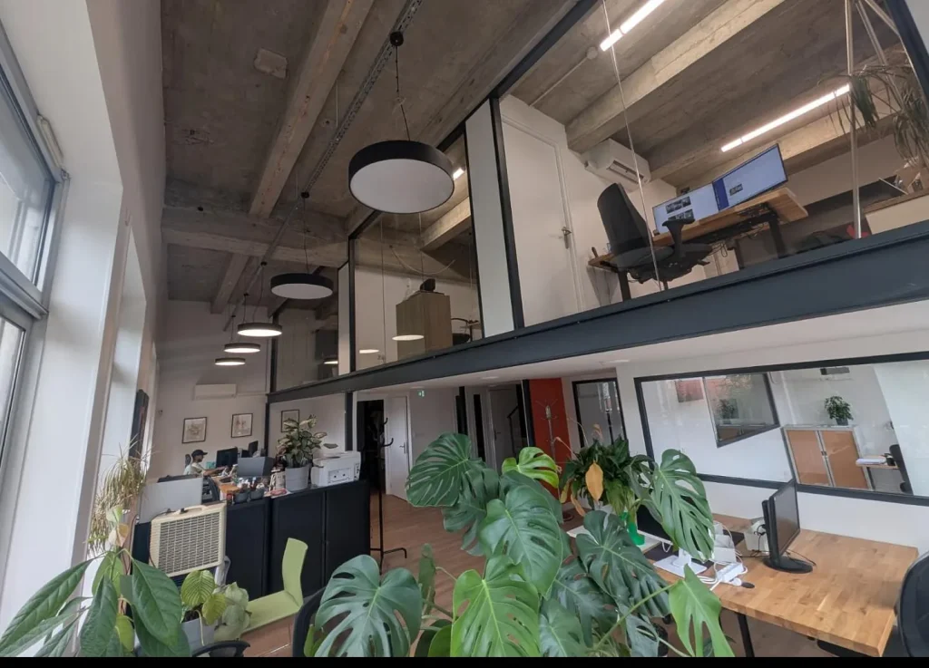 The Sutunam office in Lyon: open floor with a mezzanine, desks and plants